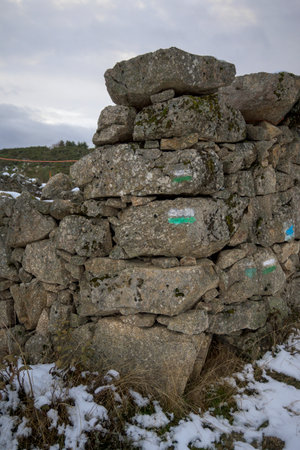 Painted hiking trail signs on an old stone wall in a natural winter landscape creating an outdoor navigation and adventure conceptの写真素材