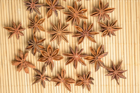 Dried star anise scattered on a bamboo mat creating a natural aromatic spice background ideal for culinary and food conceptsの写真素材