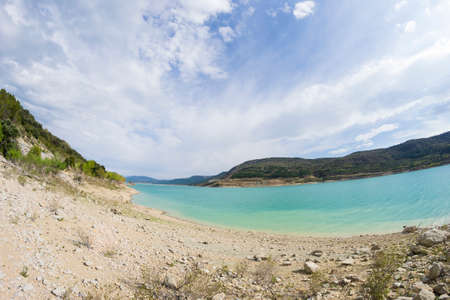 view of the lake, mountains and sky with sun and cloudsの写真素材