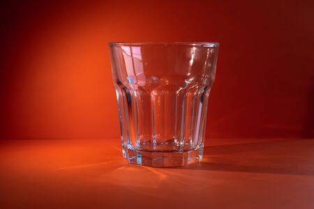 Empty glass on an illuminated orange backgroundの写真素材