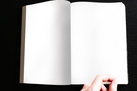 Open book with white paper on a black background with side lightの写真素材