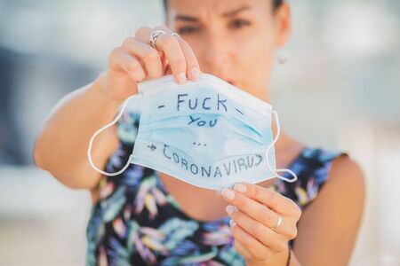 A woman holds a surgical mask with a phrase against coronavirusの写真素材