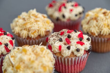 Cupcake with red and yellow ingredients, chocolate and nuts, on a grey backgroundの写真素材