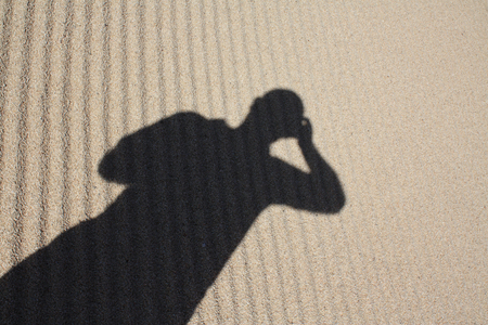 Coast Pacific sand with pattern design in a sunny day with texture and human shadow