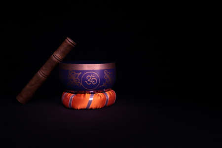 Tibetan bowl, orange cloth base, black background and reddish lighting