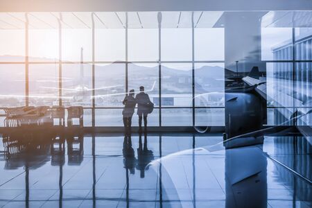 Silhouette of a couple waiting for their flight, watching the planes at the airport. Double exposure.の写真素材