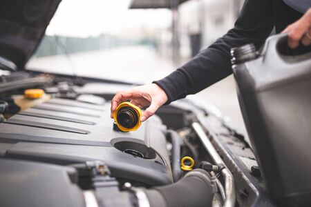 Young Caucasian woman checking the car's engine oil. Car maintenance concept.の写真素材