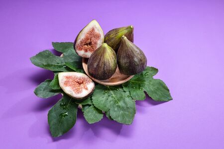 Fig jam with figs, fig leaves and white spoon with jam on purple background.の写真素材