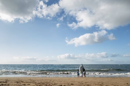 Mother with her son and daughter, looking at the sea on las canteras beach in Gran Canaria, Canary islands, Spainの写真素材