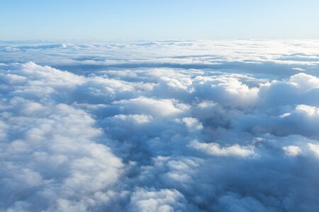 Fluffy clouds seen from above from the airplane window. Climatology and weather concept.