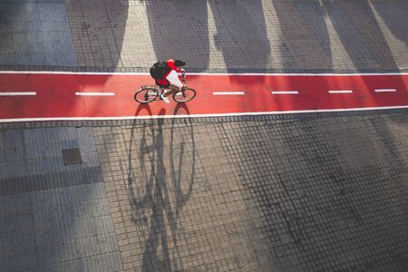 Cyclist riding on red urban bike lane in Las Palmas de Gran Canaria, bike shadow. Urban bike lane concept.の写真素材