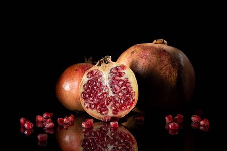 Pomegranate with pomegranate seeds on dark background with reflectionの写真素材