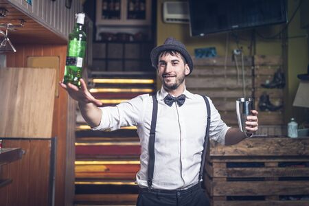 Expert barman with hat and bow tie holding a bottleの写真素材