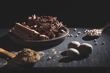Cinnamon stick, star anise, nutmeg, coriander and ground cumin, on dark background with copy space. Cooking ingredients and condiments concept.の写真素材