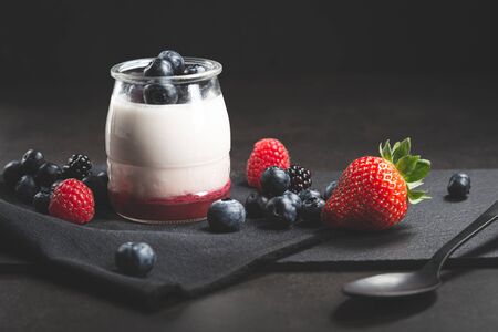 Berries yogurt with red berries spilled on black background.の写真素材