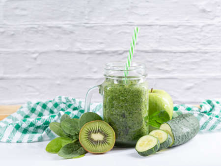 Green detox smoothie in a jar with cucumber, apple, kiwi and spinach on white background. Healthy nutrition and beverages concept.の写真素材