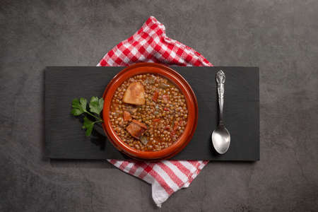 Traditional Spanish dish of lentil stew with chorizo and potatoes on a dark background. Flat lay composition.の写真素材