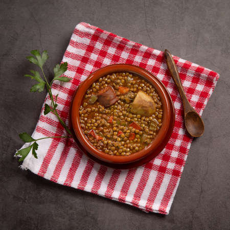 Traditional Spanish dish of lentil stew with chorizo and potatoes on a dark background. Flat lay composition.の写真素材