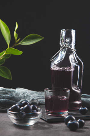 Pitcher and glass with blueberries juice on dark background.