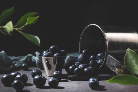 Blueberries spilled from metal jar on dark background.の写真素材