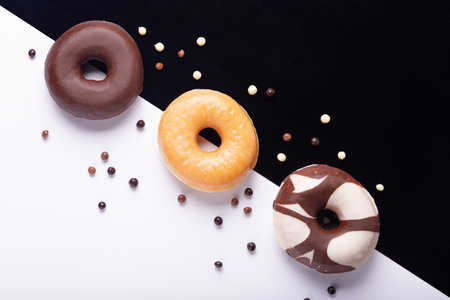 Flat lay composition of three donuts on black and white background.の写真素材