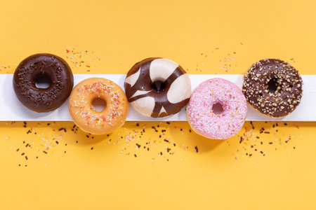 Flat lay composition with mixed donuts on yellow background.の写真素材