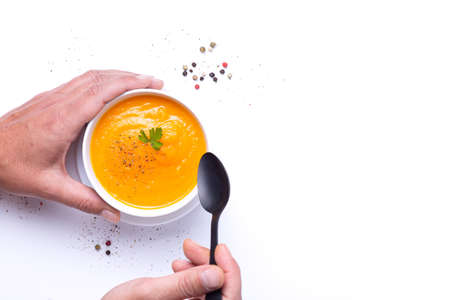 Man's hands scooping carrot soup. Top view with copyspace.の写真素材