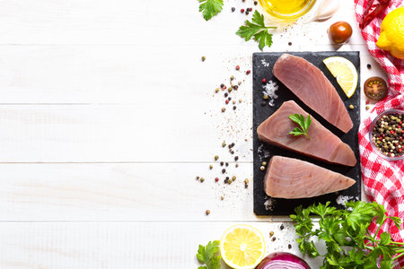 Fresh raw tuna steaks on black slate plate on white background. top view with copyspace.の写真素材
