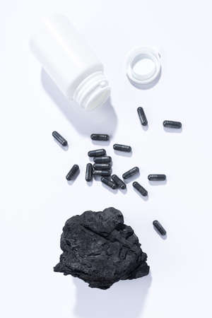 Flat lay composition of vegetable carbon capsules on white background. Portrait format. Dietary...
