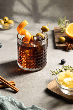 Vermouth cocktail with snacks and ingredients on concrete background. Portrait format. Typical...
