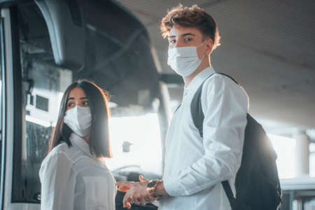 Young boys with face masks waiting for the bus to travel to their destinationの写真素材