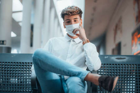 Young blond boy with face mask worried at the bus stationの写真素材