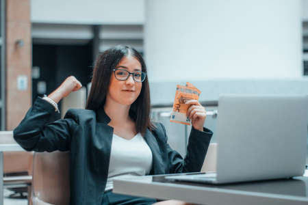 Happy businesswoman girl manages to earn money online in a professional wayの写真素材