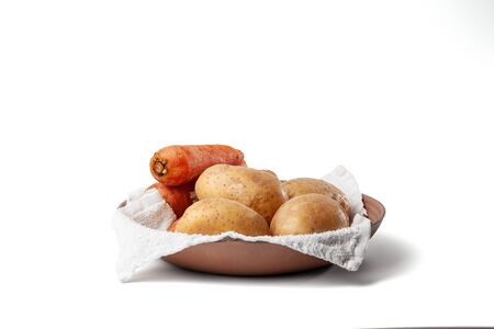 boiled potatoes and carrots on a towel in a plate on the white backgroundの写真素材