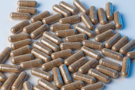 brown capsules pills on a white background with blue lights