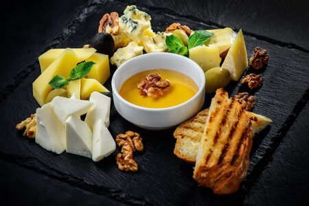 Cheese plate with cheeses Dorblu, Parmesan, Brie, Camembert and Roquefort in serving on the black textured backgroundの写真素材