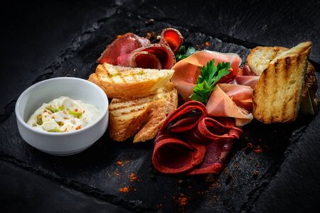 meat delicatessen plate arranged on the black textured backgroundの写真素材