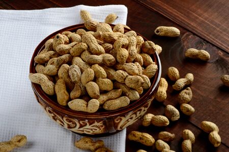 Peanuts in a bowl on a dark background. Peanuts in a shell. Healthy food.の写真素材