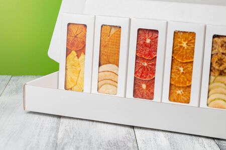 Boxes of fruit chips lie on a white wooden background, back light green backgroundの写真素材