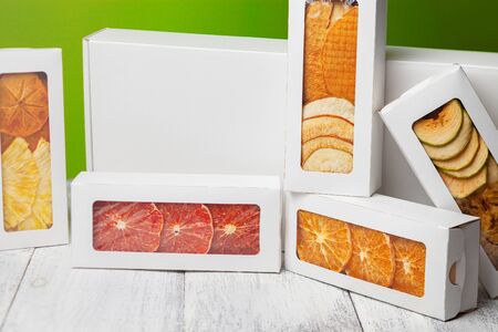 Boxes of fruit chips lie on a white wooden background, back light green backgroundの写真素材