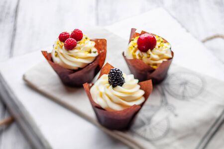 muffins with Belgian chocolate and white chocolate cream and mascarpone with berries on a wooden trayの写真素材