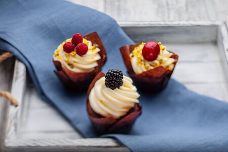 muffins with Belgian chocolate and white chocolate cream and mascarpone with berries on a wooden trayの写真素材