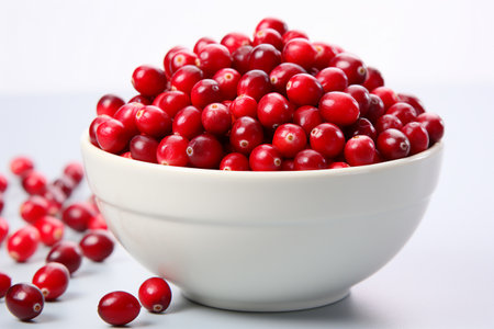 Close-up of fresh cranberries in a white bowl. Bright natural light, red berries as sole point of interest. Crisp and minimalist.の素材