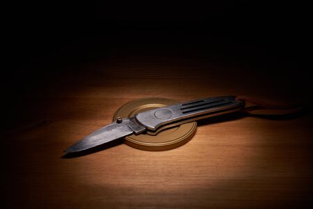 Silver jackknife on a wood table with a top lightの写真素材