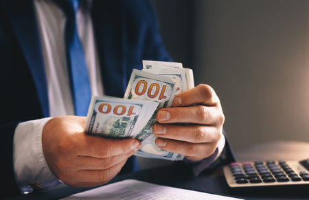 Businessman counting money in office. Close up of male hands counting money.の写真素材