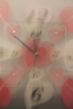 Double exposure of a clock with white and red hearts