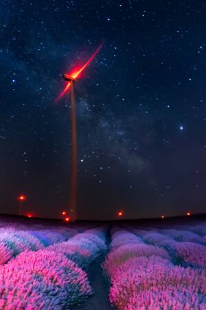 Beautiful landscape of a starry night with milky way and blue sky over a field of lavender and red lights of wind turbines, Gorun, Bulgariaの写真素材