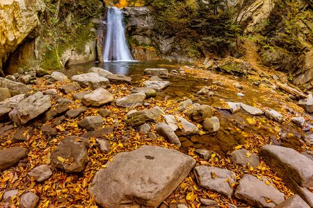 Long exposure view of the beautiful Pruncea CaÅoca Waterfall with fallen leaves in an autumn landscape,Siriu, Buzau, Romaniaの写真素材