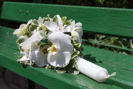 Beautiful arrangement of white orchids, green leaves and a candle on a brown backgroundの写真素材