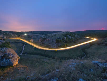 Light trails on the road and a beautiful evening sky over the hills of Dobrogea, Cheile Dobrogei, Romaniaの写真素材